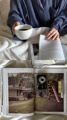 an open book with pictures and a cup of coffee on it, sitting on a bed