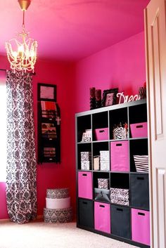 a room with pink walls, black and white storage bins, and a chandelier