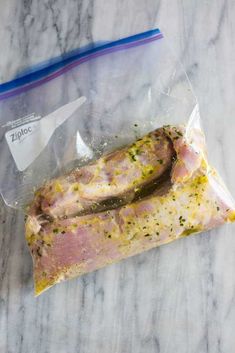 a piece of meat in a plastic bag on a marble counter top next to a toothbrush