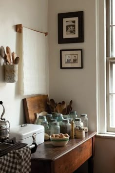 an old fashioned kitchen with many jars and utensils on the table in front of a window