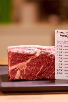 a piece of meat sitting on top of a wooden cutting board next to a price label