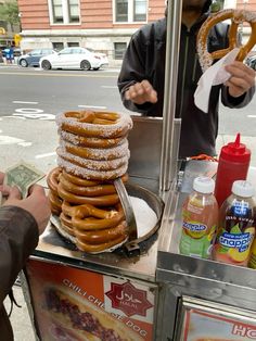 a man is selling doughnuts at an outdoor food stand on the street corner