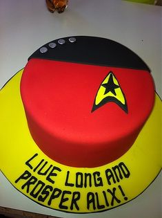 a star trek themed birthday cake on a white tablecloth with an orange, yellow and black design