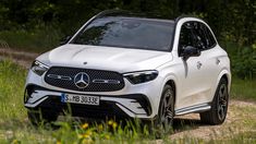 the front end of a white mercedes gle suv parked on a dirt road with trees in the background