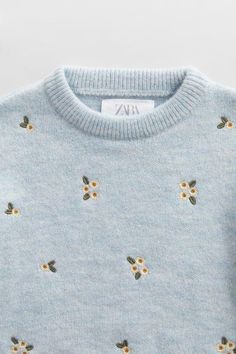 a blue sweater with yellow flowers on it