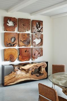 a dining room table and chairs in front of a wall with wood pieces on it