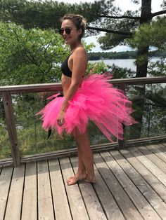 a woman standing on a deck wearing a pink tutu skirt and black tank top