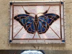 a stained glass butterfly hanging on the side of a building