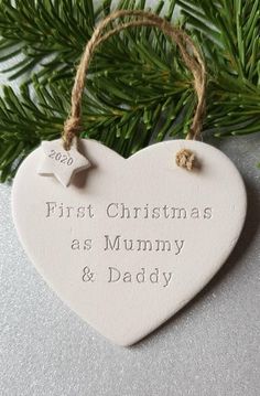 a ceramic heart ornament hanging from a christmas tree with the words'first christmas as mum and daddy '