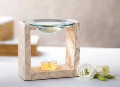 a candle holder with a glass bowl on it and a white rose in the background