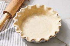 an uncooked pie crust in a bowl next to a rolling pin