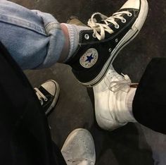 two people standing next to each other wearing black and white converse shoes with blue stars on them