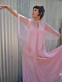 a woman wearing a pink dress and holding her arms out