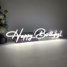 the happy birthday sign is lit up with flowers