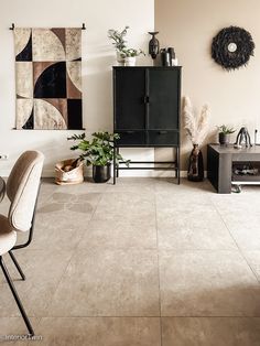 a living room filled with furniture and art work on the wall above two black cabinets