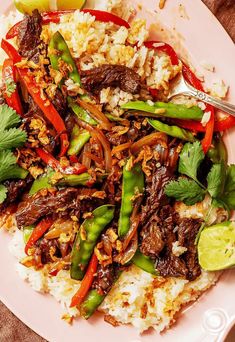 a white plate topped with meat and veggies next to rice on top of a table