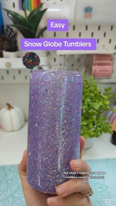 someone holding up a purple tumbler with glitter on it and the text easy snow globe tumblers