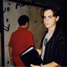 a young man holding a folder in front of lockers