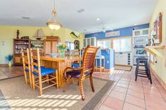 a dining room table and chairs in front of a kitchen with yellow walls, tile flooring and blue cabinets