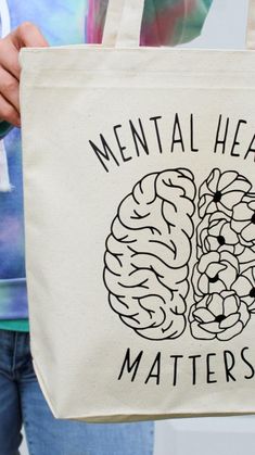 a person holding a tote bag that says mental health matters