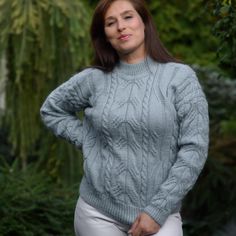 a woman wearing a gray cabled sweater posing for the camera with her hands on her hips