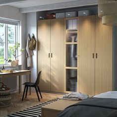 a bedroom with a bed, desk and closets in the corner next to a window