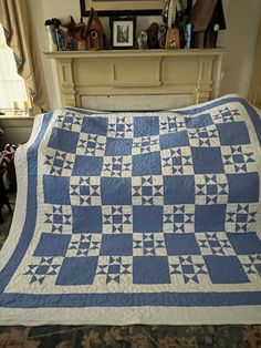 a blue and white quilt sitting on top of a bed next to a fire place