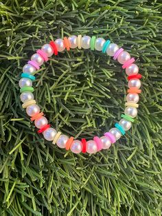 a bracelet with multicolored beads on top of grass