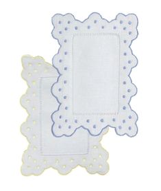 two white napkins with blue dots on the edges and one has a square shape