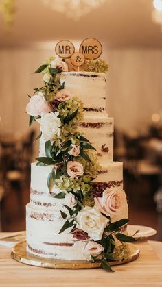 a wedding cake with flowers and mr and mrs signs on top is sitting on a table