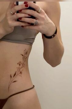 a woman with tattoos on her stomach looking at her cell phone