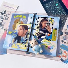 an open book with stickers on it next to a cell phone and other items