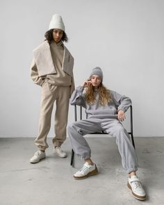 two people sitting on a chair with one wearing a hat and the other in sweatpants