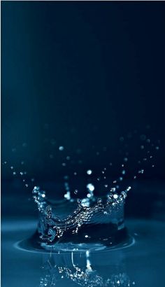 water splashing on top of a blue surface in the middle of the image, with dark background