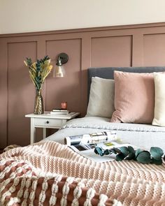 a bed that has some pillows on top of it in a room with pink walls