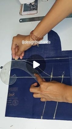 a person cutting paper with scissors on top of a blue piece of material that has been cut into smaller pieces