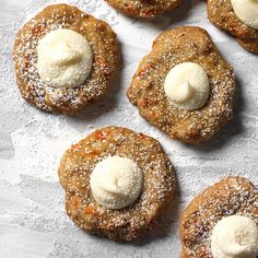 several pastries with powdered sugar and butter on top sit on a piece of paper