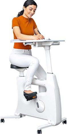 a woman sitting at a desk on an exercise bike