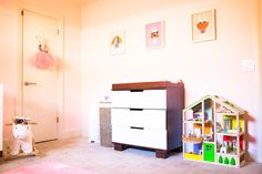 a baby's room with a dresser and toy house