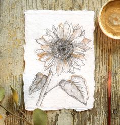 a piece of paper with a drawing of a sunflower on it next to a spoon