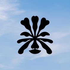 a black and white photo of an upside down clock on a blue sky with clouds in the background