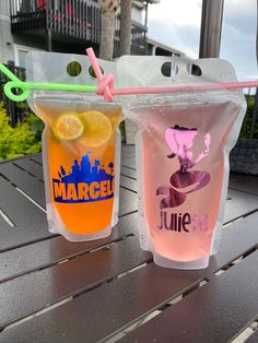 two plastic cups filled with drinks sitting on top of a wooden table next to each other