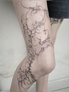 a woman's legs with tattoos on them and her leg is covered in black ink