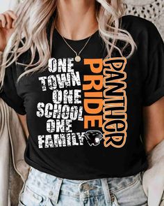 a woman wearing a black t - shirt with orange and white lettering that says, one town