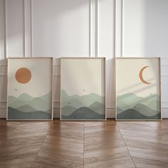 three framed art pieces on the floor in front of a wall with mountains and a moon