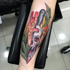 a person with a knife and skull tattoo on their arm