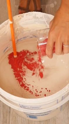 a person pouring red liquid into a bucket