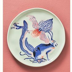 a blue and white plate with an image of two birds flying over it on a pink wall