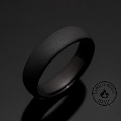 a black wedding ring with a white center on a dark background and a logo for the company