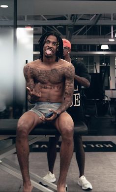 a man sitting on top of a bench in a gym with another man standing behind him